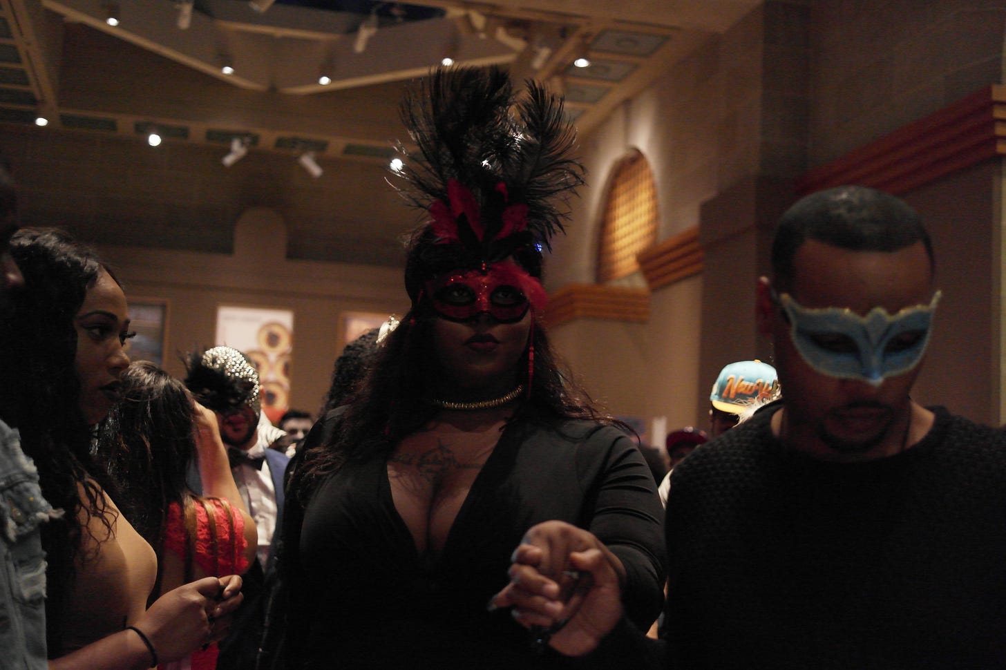 A photograph of ballroom participants attending a ball. The pictured participants appear to be Black and wear colorful masks with dark outfits.