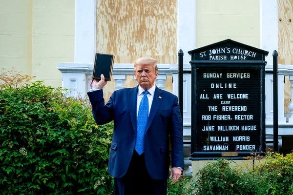 Former President Donald J. Trump holding a Bible in his right hand. A sign for St. John’s Church is behind him.