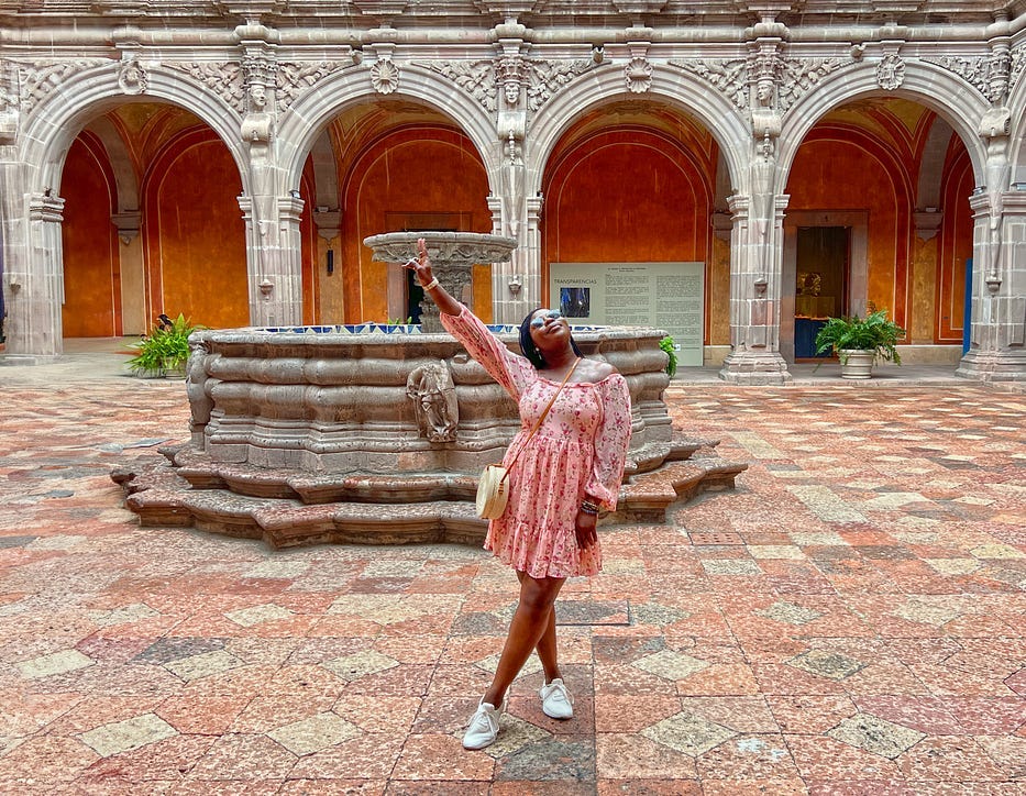 Woman holding up hat in the courtyard of a museum in Mexico.