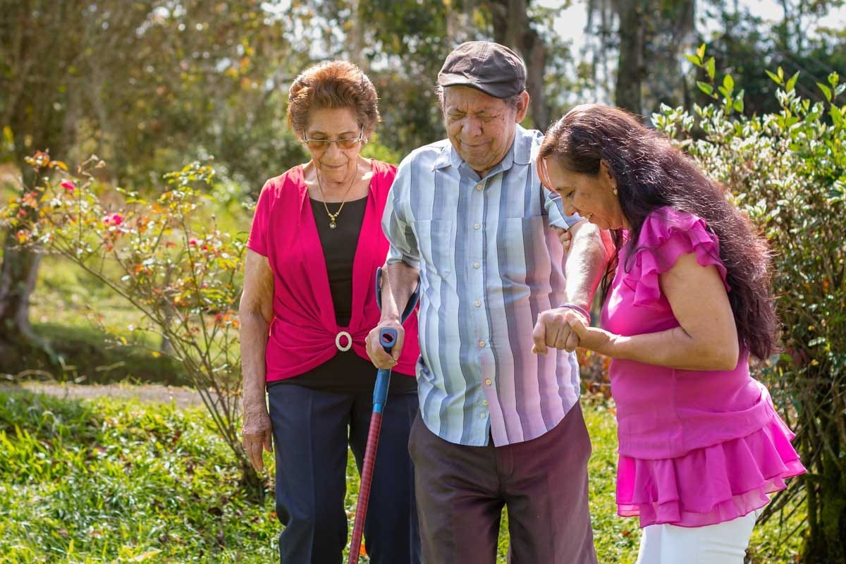 Woman accompanying her elderly parents on a walk in the countryside. Active aging and family support.