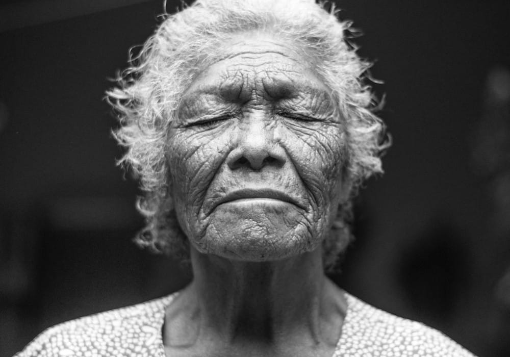 Black and white portrait of elderly woman with eyes closed in contemplation