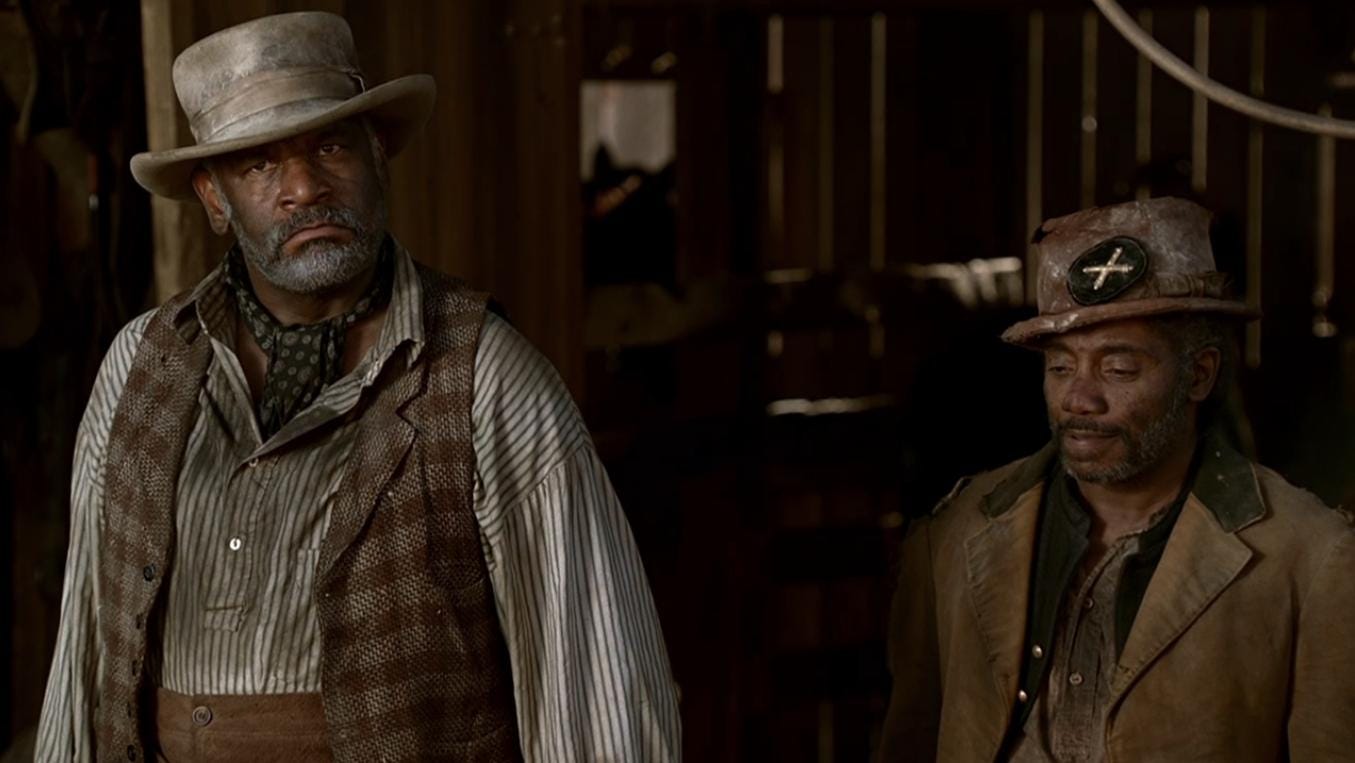 This image shows livery owner Hostetler (played by Richard Gant) on the left and his friend Samuel Fields (played by Franklin Ajaye) on the right. Both men stand in the entrance to Hostetler's stable.