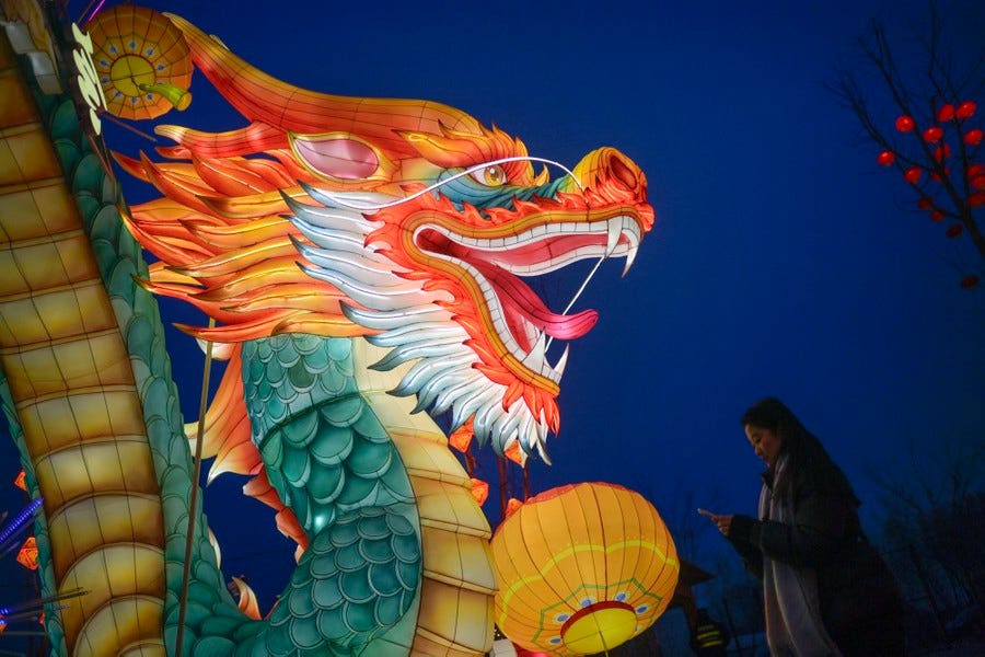 A woman stands next to a brightly lit dragon figure.