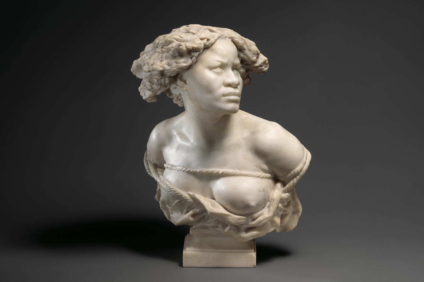 Marble bust of African woman, left breast partially exposed, arms bound behind her