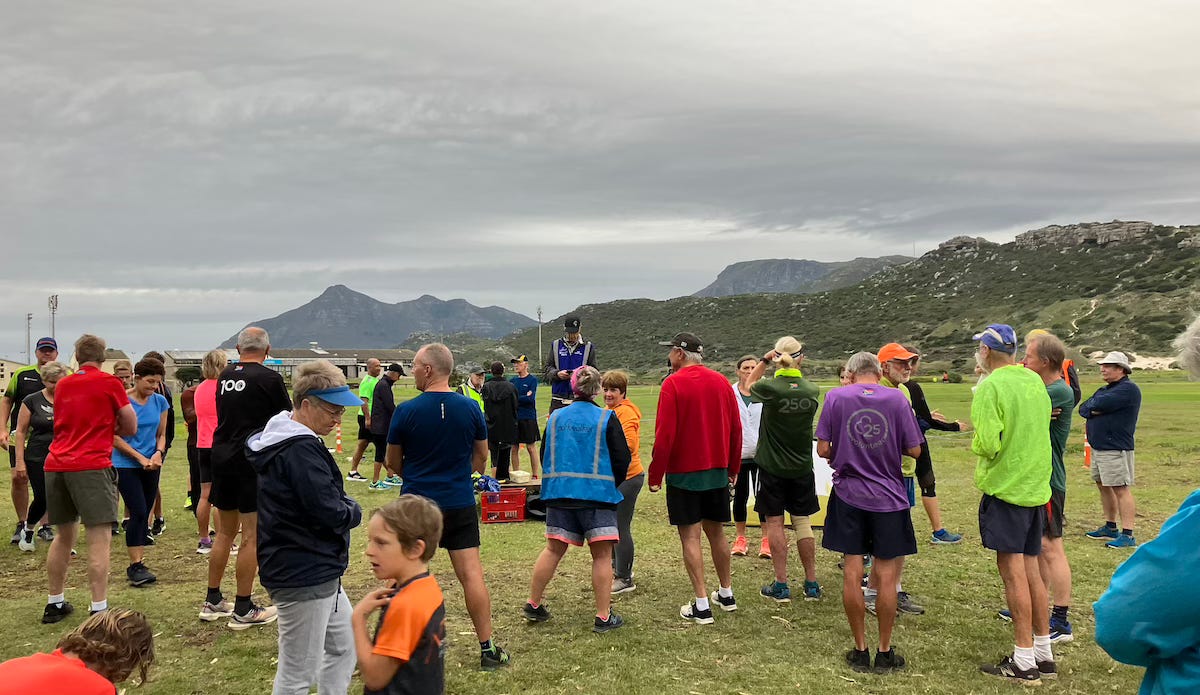 Runners gathered for the briefing with mountains in the distance, centre and right