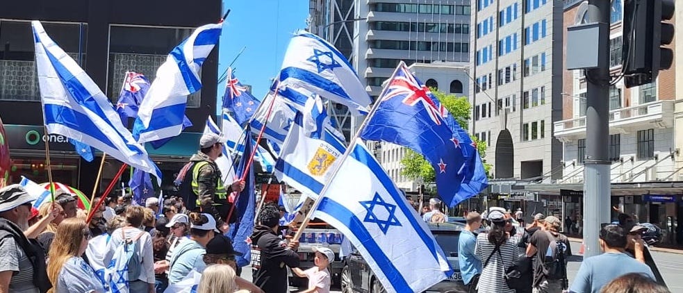 Image of rally in solidarity with Israel held in New Zealand, Israeli flags alongside the New Zealand flag