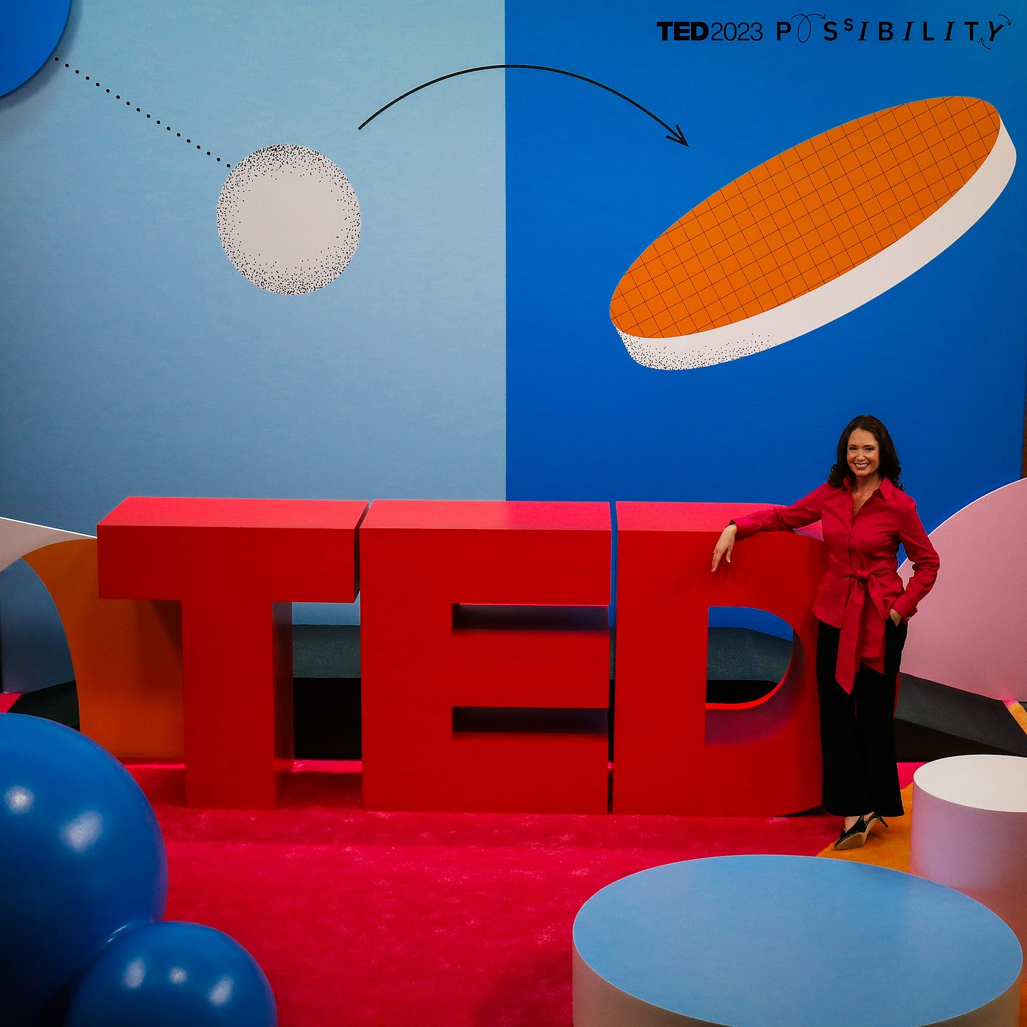 Jennifer leaning on giant TED sign on photo stage