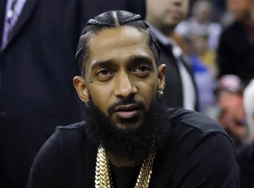 FILE - Rapper Nipsey Hussle attends an NBA basketball game between the Golden State Warriors and the Milwaukee Bucks in Oakland, Calif., March 29, 2018. Eric R. Holder Jr., who was convicted last year of fatally shooting Hussle in 2019, is scheduled to be sentenced Wednesday, Feb. 22, 2023, in a Los Angeles courtroom. (AP Photo/Marcio Jose Sanchez, File)