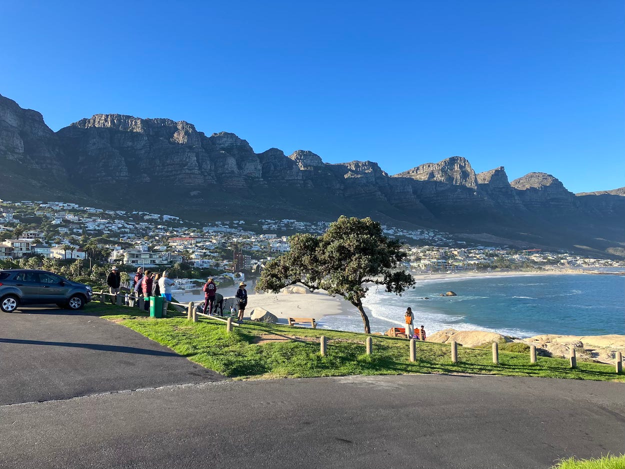 Picture from a car park, of a bay overlooked by mountains, near Cape Town