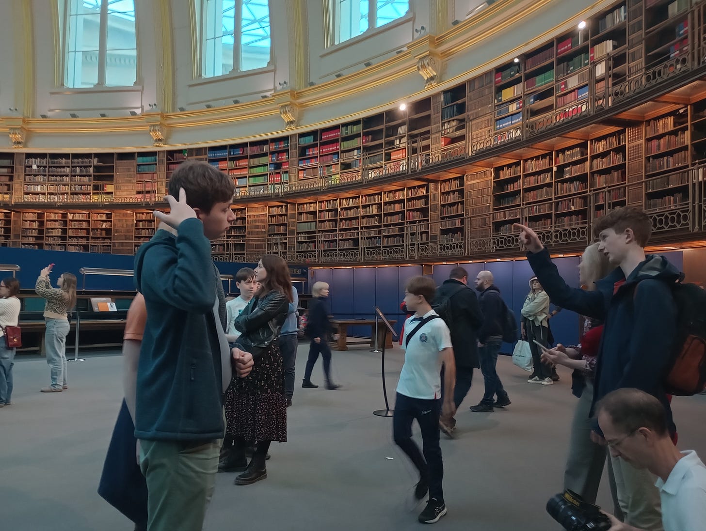 People wandering into the Round Reading Room,surrounded by books and high windows