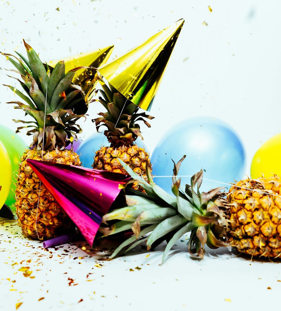 Three pineapples in colorful party hats