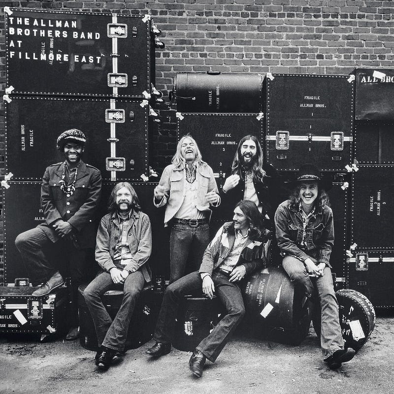 Cover for the Allman Brothers Band’s At Fillmore East album. The band is laughing while sitting in front a stack of road cases. From left to right: Jaimoe, Duane Allman, Gregg Allman, Dickey Betts, Berry Oakley, Butch Trucks