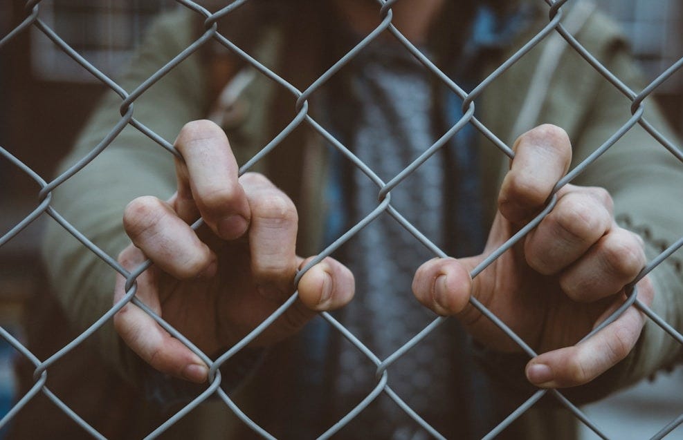 person behind mesh fence