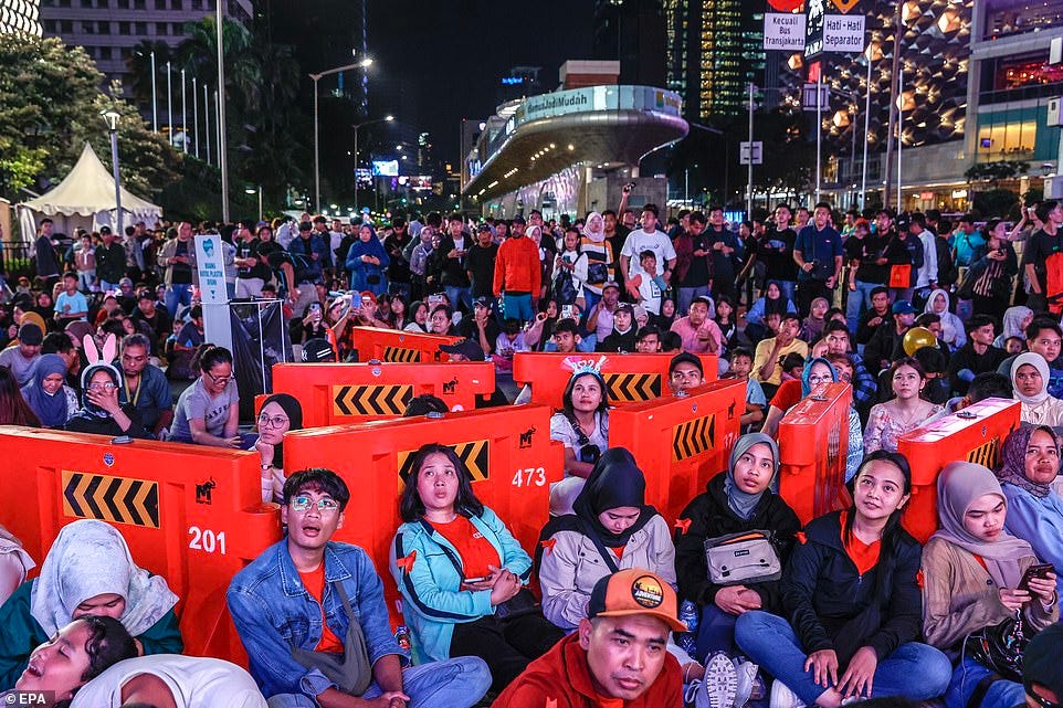 INDONESIA: People sit among security barriers on the street during the New Year's Eve celebrations at Bundaran Hotel Indonesia roundabout in Jakarta, Indonesia