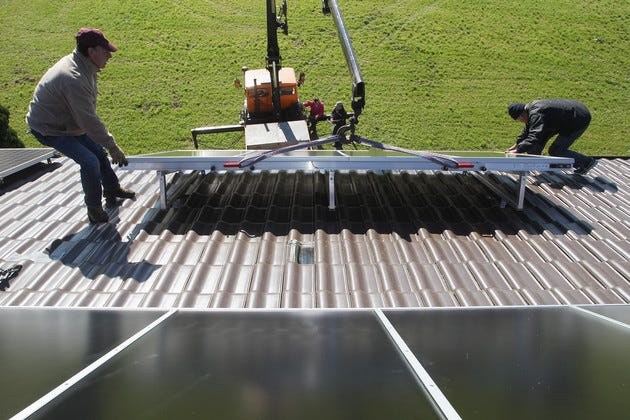 Workers install solar power modules for producing heat on the roof of a house in Wessling, Germany.