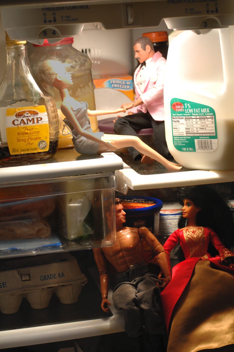 Barbies and G.I. Joes in the refrigerator, looking like they are lost in conversation. One man seems to be proposing marriage.