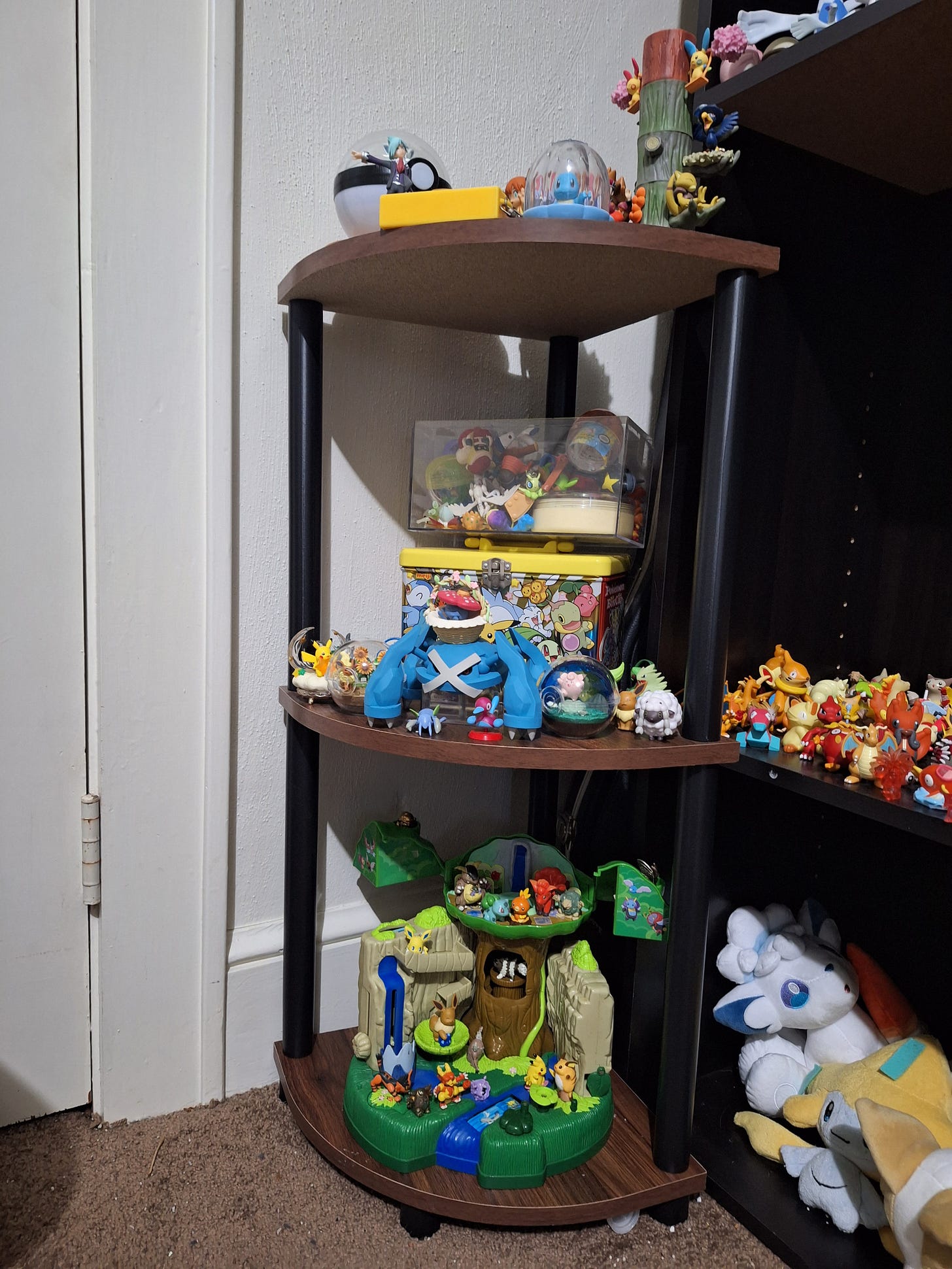 Miles has a smaller shelf filled with figures, such as a large Metagross figure, and a world scale figure of Steven from Pokémon Ruby & Sapphire!