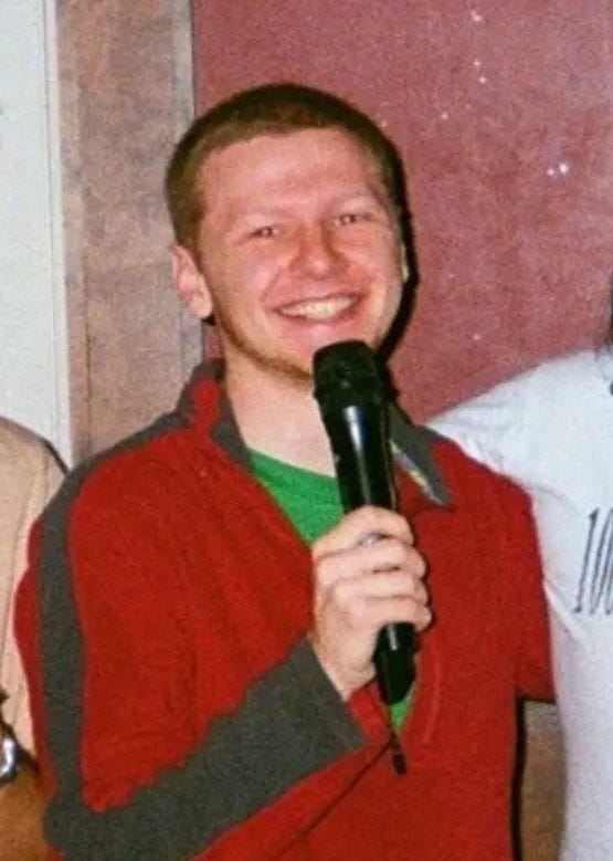 Aaron Bushnell, smiling broadly and holding a microphone.