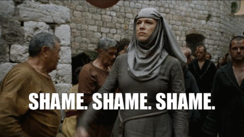 cena da série Game of Thrones onde uma Freira anda na rua tocando um sino, ela se veste de cinza e na rua pessoas acomapnham ela. na legenda está escrito: SHAME. SHAME. SHAME.