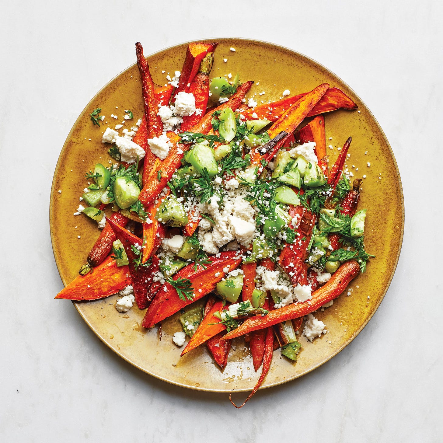 Roasted carrots and root vegetables with green salsa on a gold plate