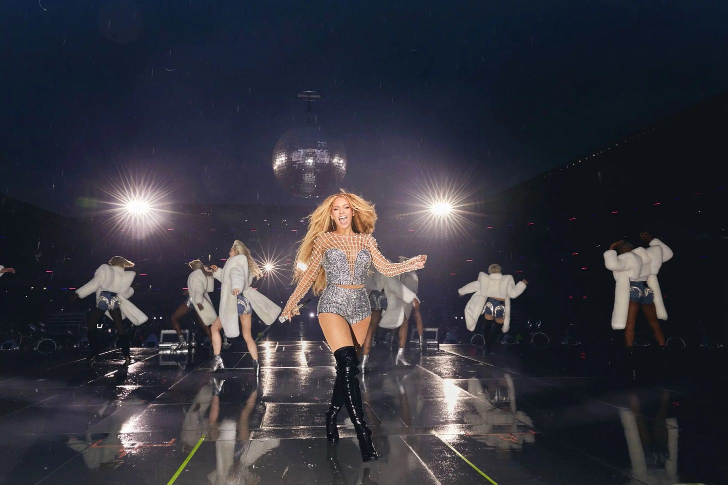 Beyonce smiles and swaggers down the mainstage, dressed entirely in silver. Her dancers and a giant disco ball shimmer behind her. 