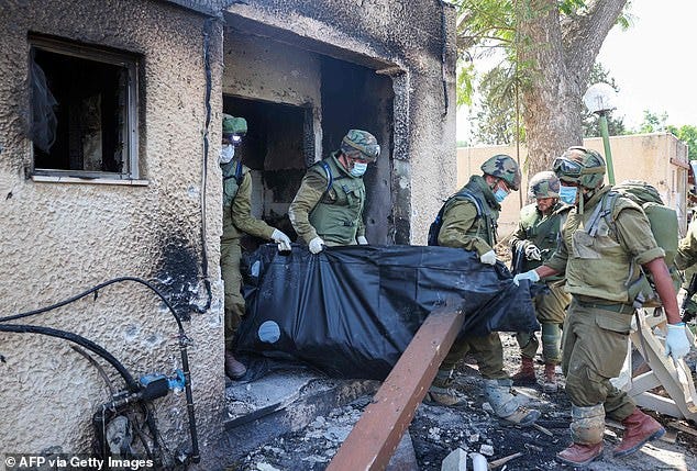 Troops remove the bodies of victims, killed during an attack by Hamas terrorists in Kfar Aza, on Tuesday