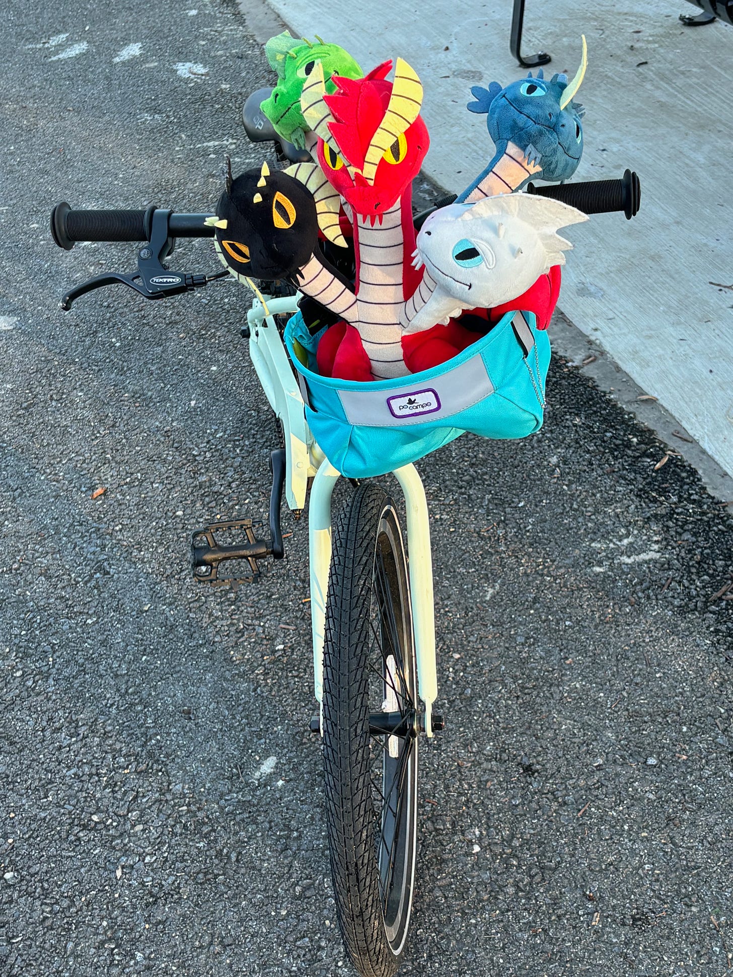 A children's bike with a five-headed dragon in a bike bag on the front