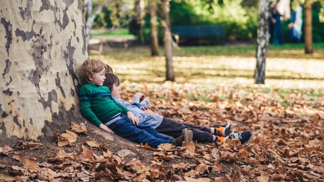 kids resting against tree