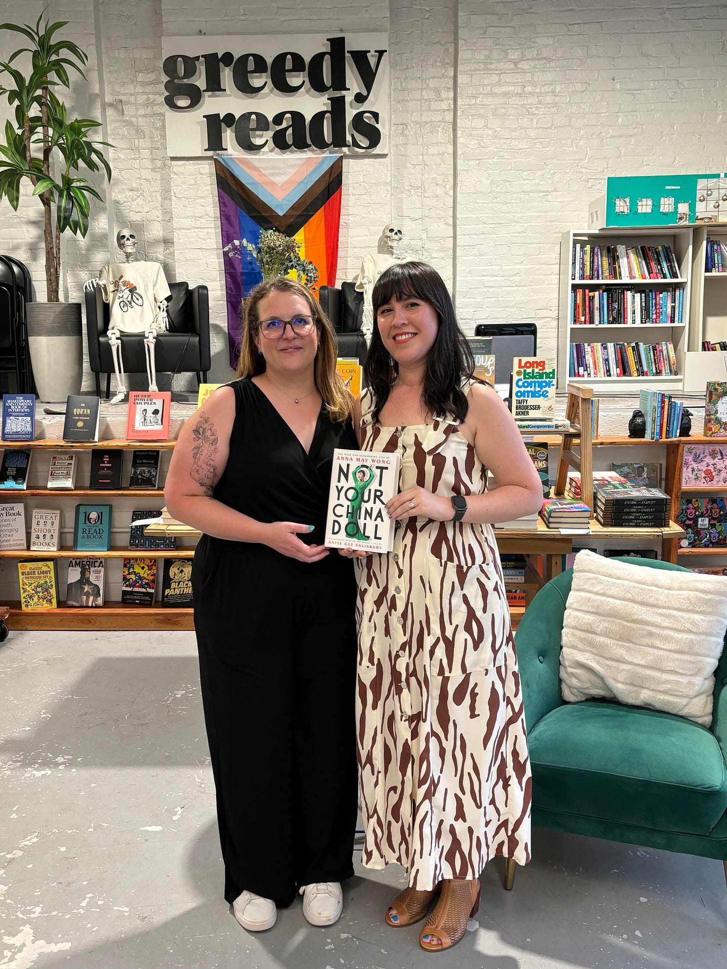 Two women stand holding a copy of Not Your China Doll at a bookstore