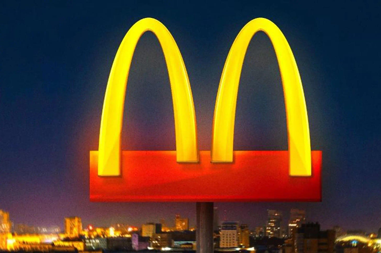 The golden arches on a red billboard, with a cityscape in the background