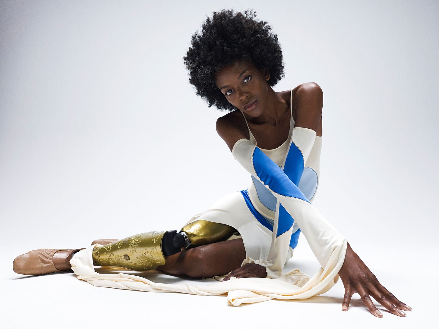 A Black woman with a gold-plated prosthetic leg crosses her legs and arms in a selfie.