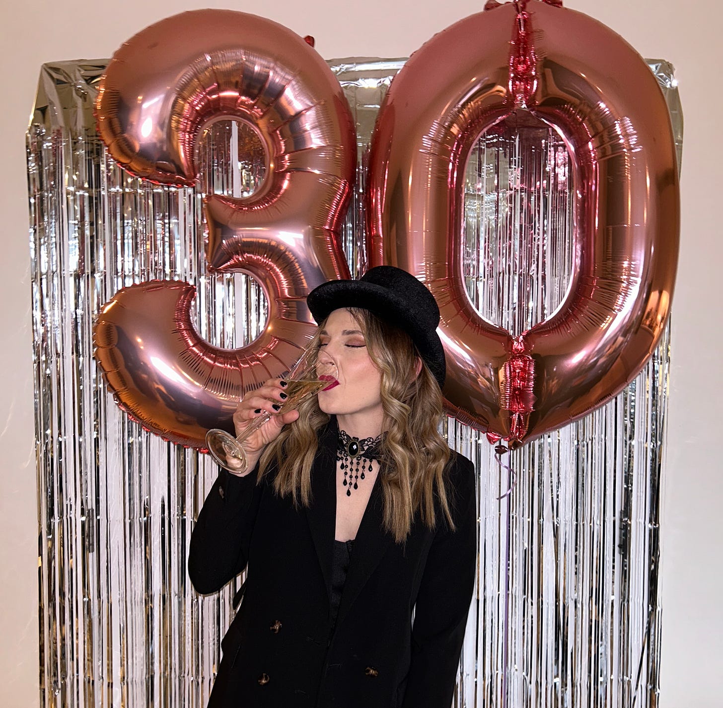 Image of Jess drinking sparking wine with giant 3 0 balloons behind her.