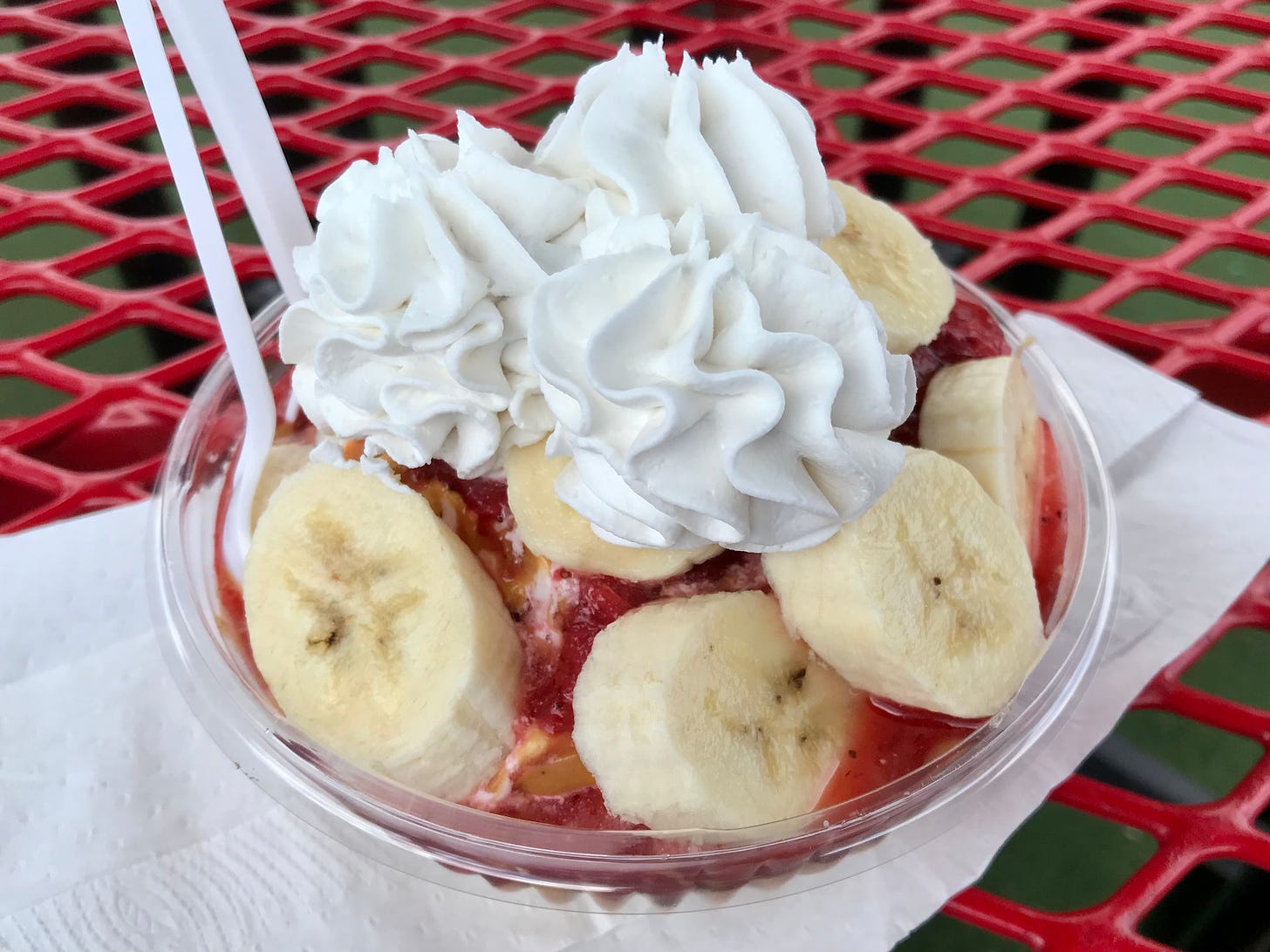 Sundae topped with strawberry sauce, peanut butter, bananas, an vegan whipped cream.