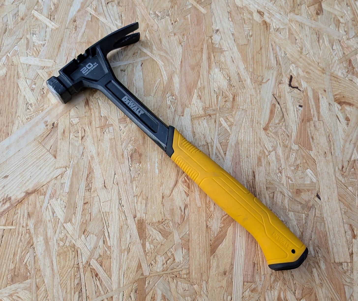 Close-up of a yellow and black DeWalt 20oz hammer, a well-balanced tool for nail driving.