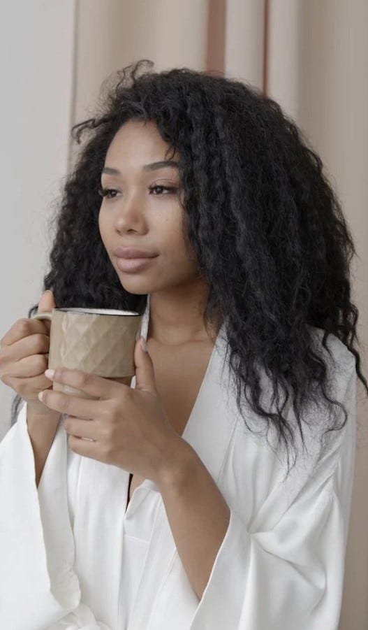 Woman soft complexion, dark hair, white robe, drinking coffee