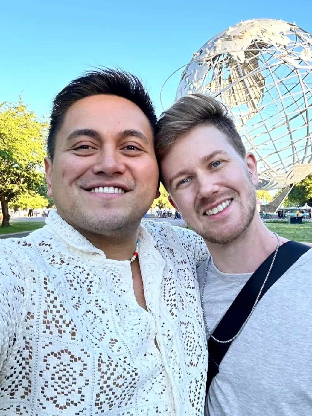 two gay guys smiling in front of sculpture in Queens NY