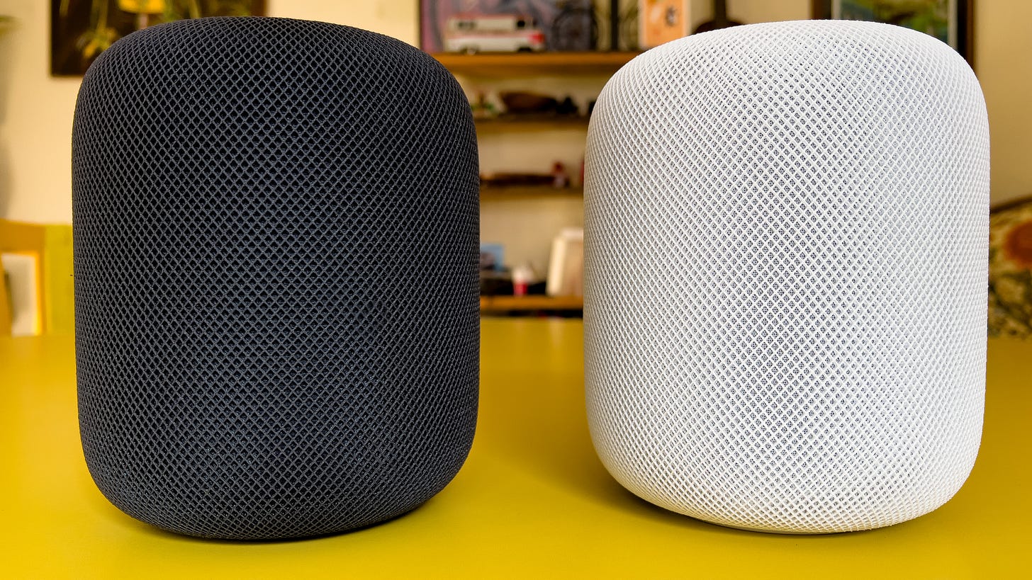 Two homepods on a table: midnight (left) and white (right)