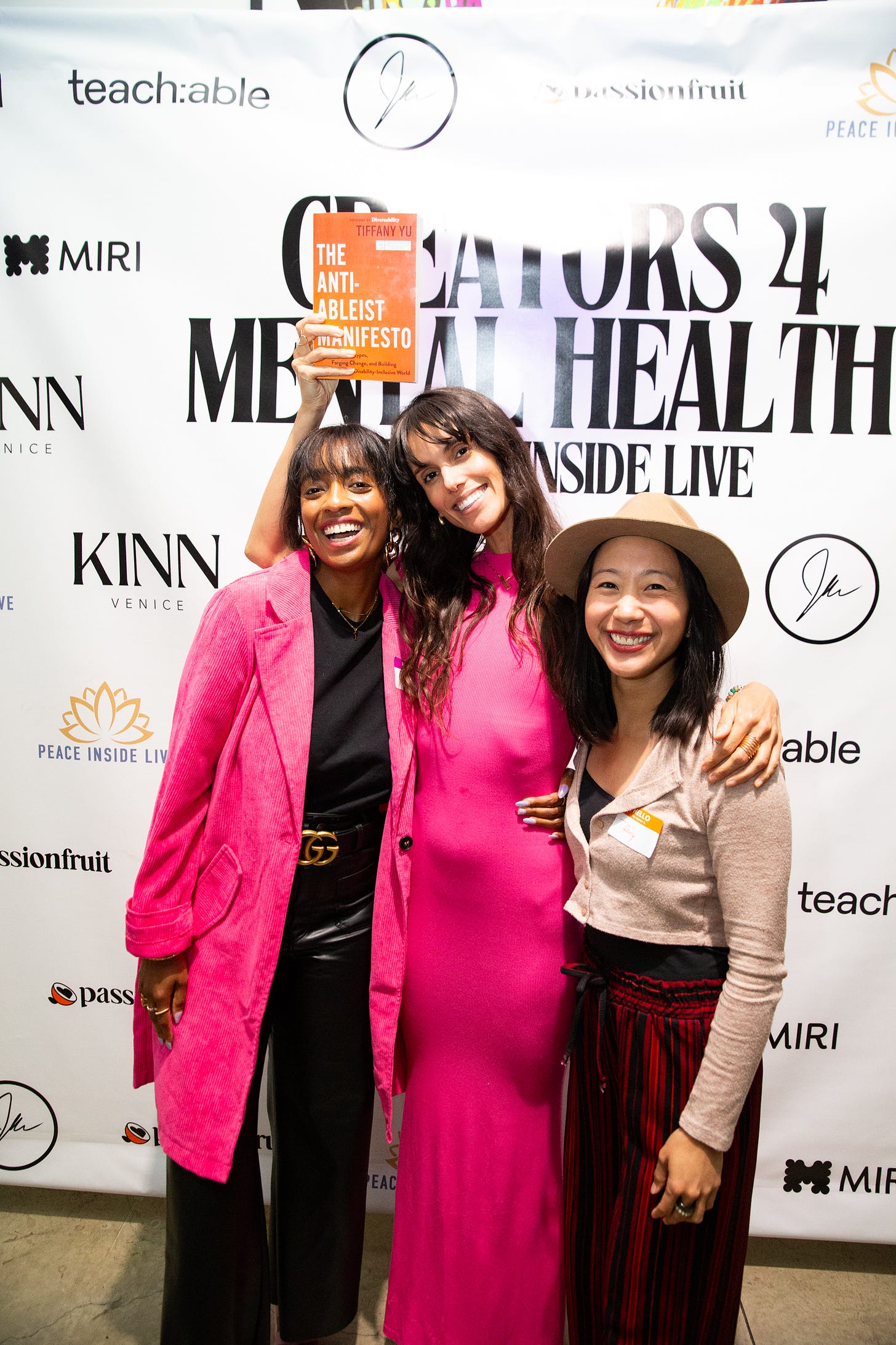 liz and tiffany hold her book in front of step and repeat