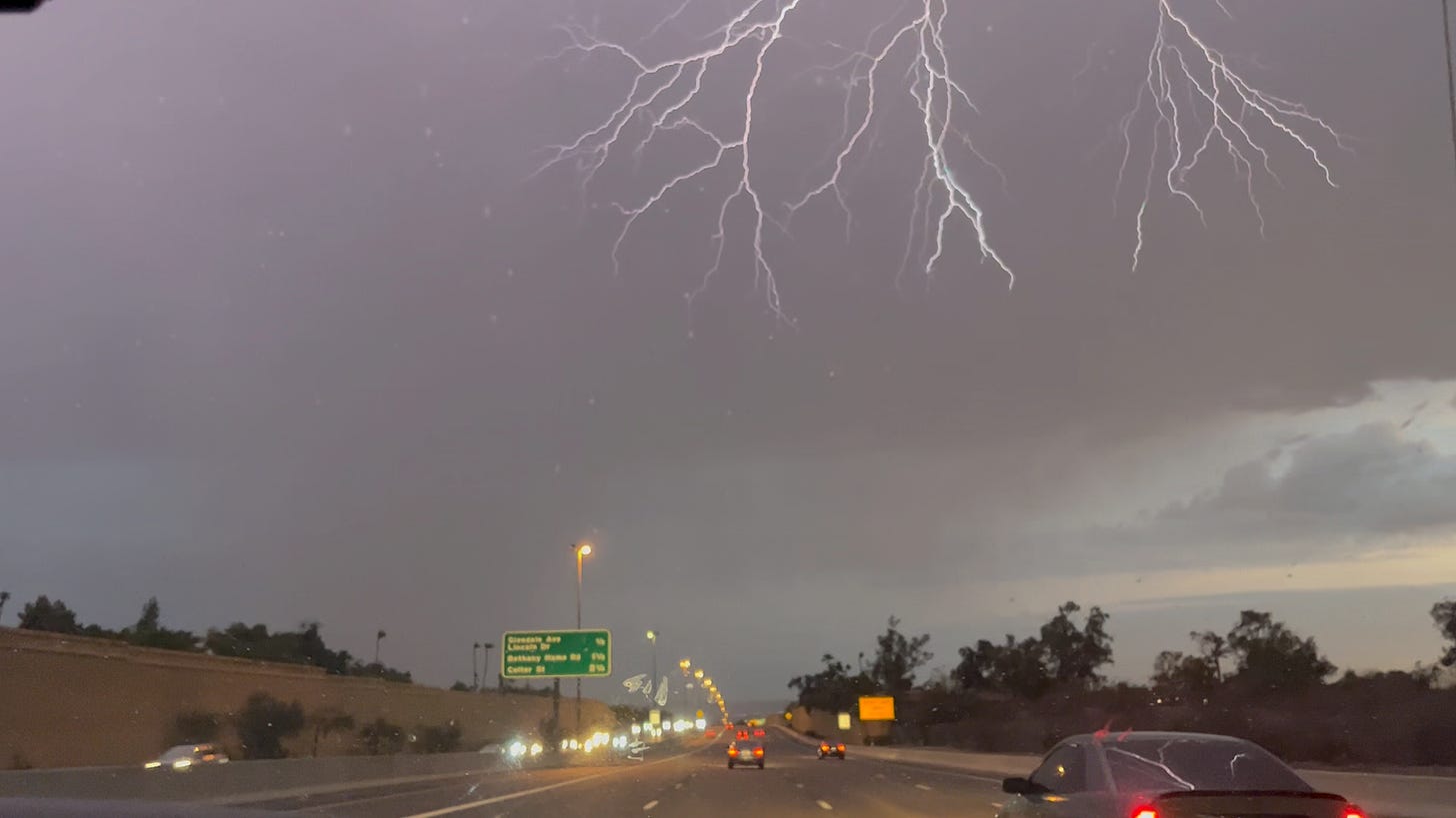 lightning strikes above the highway, a splintered strike that looks like a tree branch with many off shoots