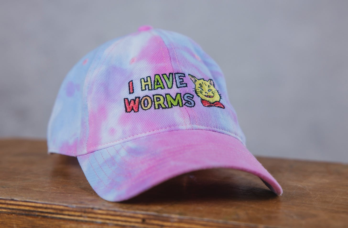 Tie dye rainbow cap, with I HAVE WORMS printed on it