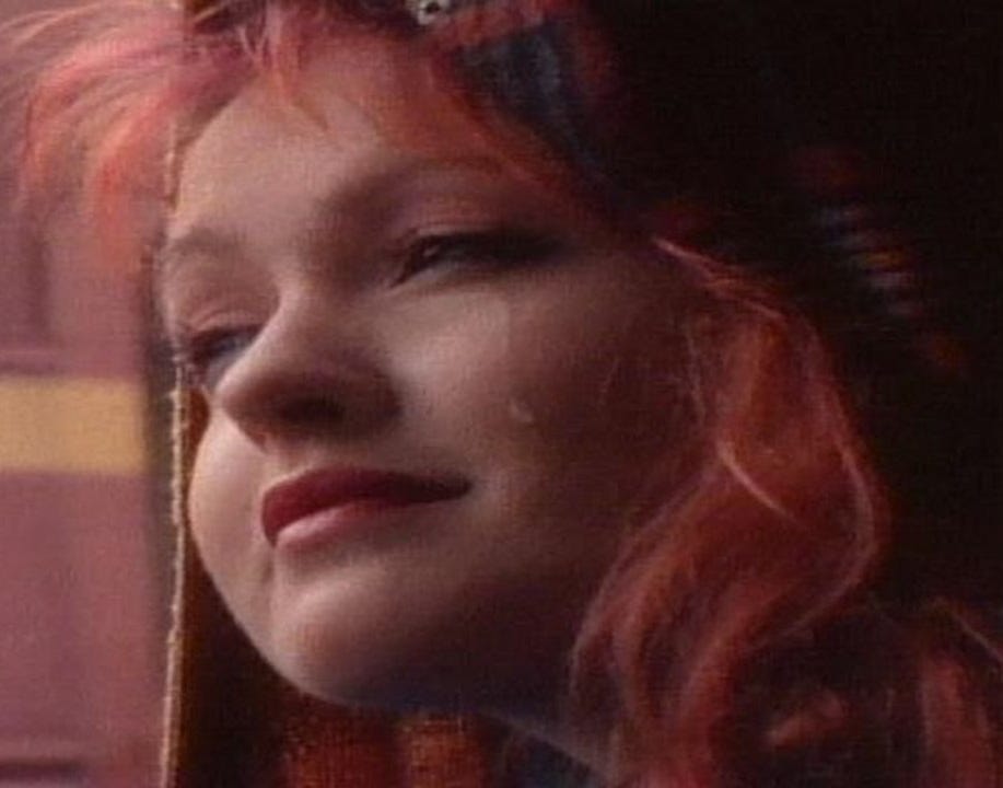 Close up of Cyndi Lauper looking out a window from the Time After Time music video.