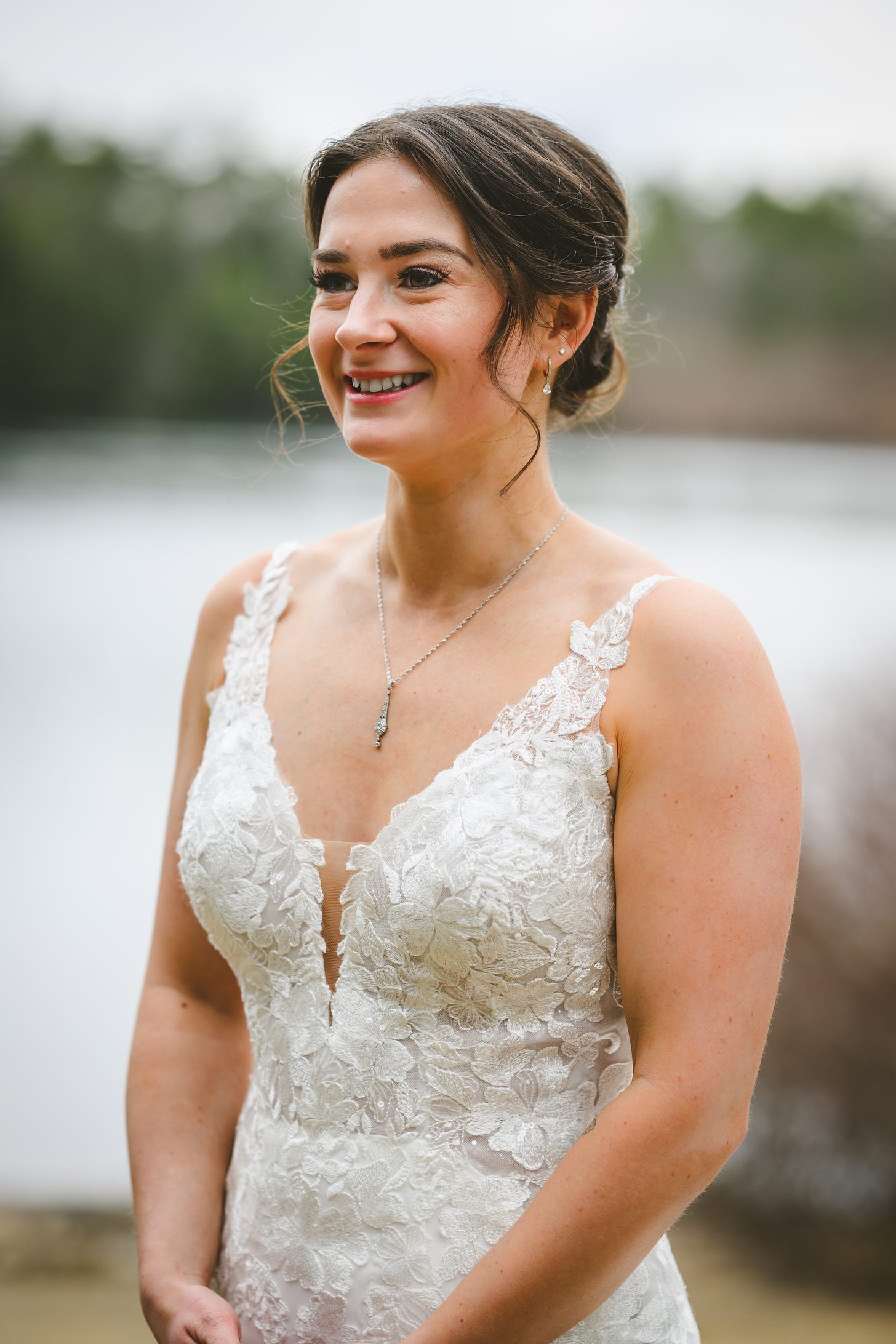 A bride in her wedding dress standing in front of a lake