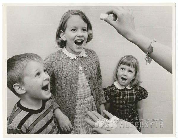 Children taking the polio vaccine on sugar cubes, 1964.