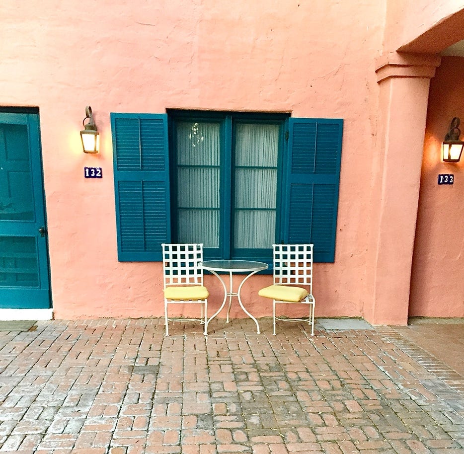 A table and chairs in front of a pink building

Description automatically generated