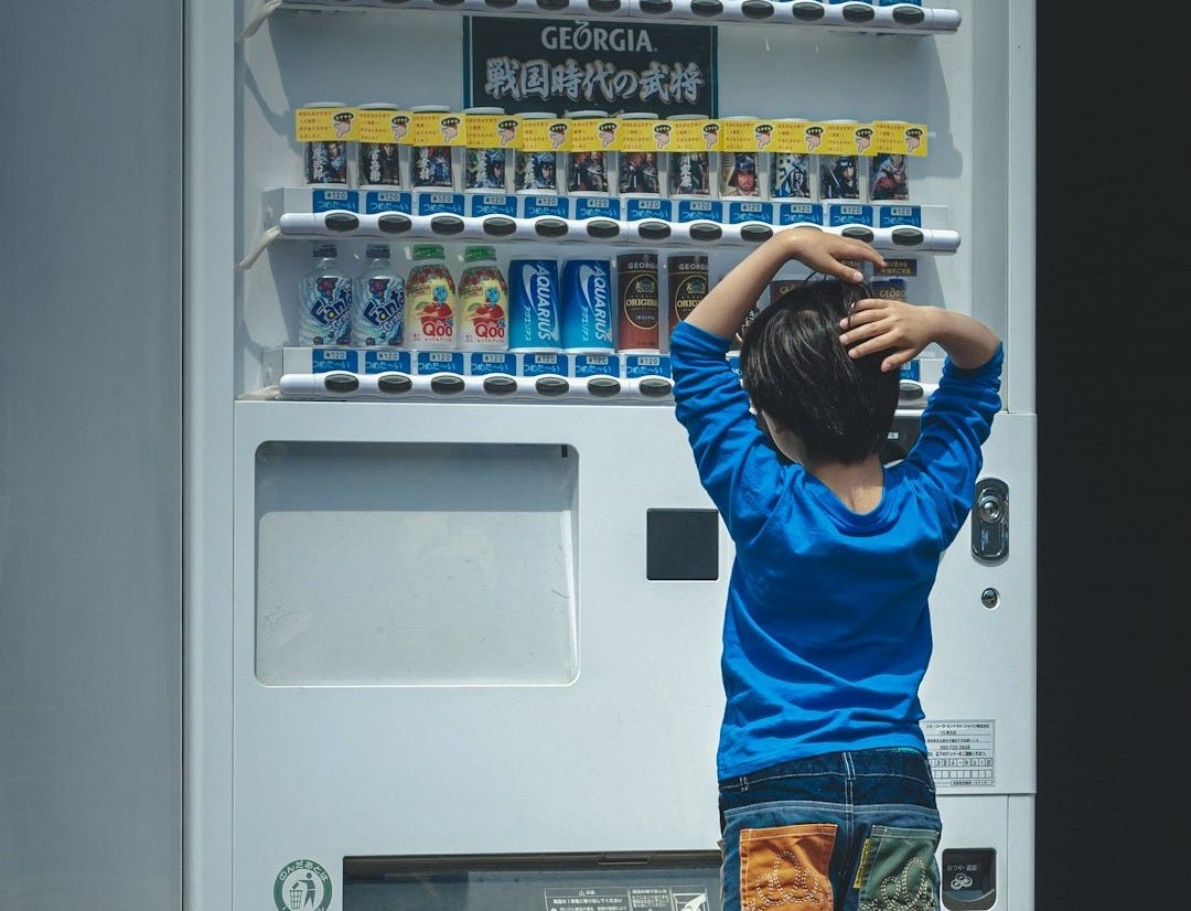 a young boy standing in front of a vending machine a young boy standing in front of a vending machine