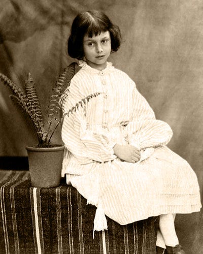 ルイス・キャロルによって撮影されたアリス・リデルの写真。黒髪の少女が首をかしげて座っている。