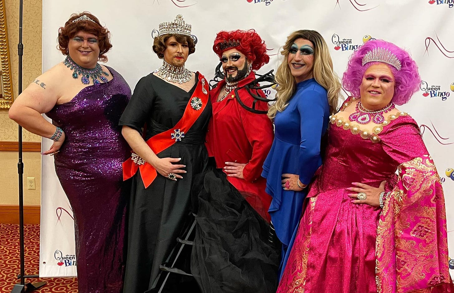 In royal dresses and tiaras, the Stilettos drag troupe poses for a photo.