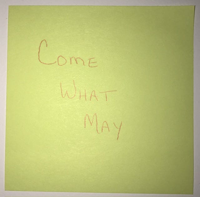 A yellow sticky note with the words, “Come What May”