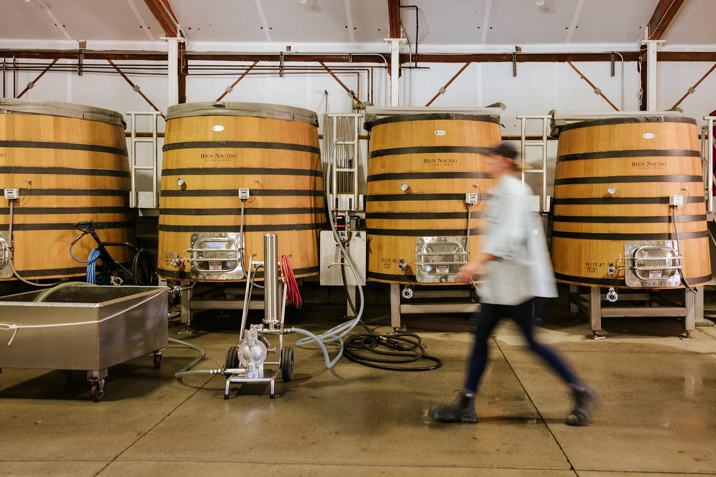 A blurred woman walks past a row of oak foudres at Bien Nacido Estate Winery. A blurred woman walks past a row of oak foudres at Bien Nacido Estate Winery.