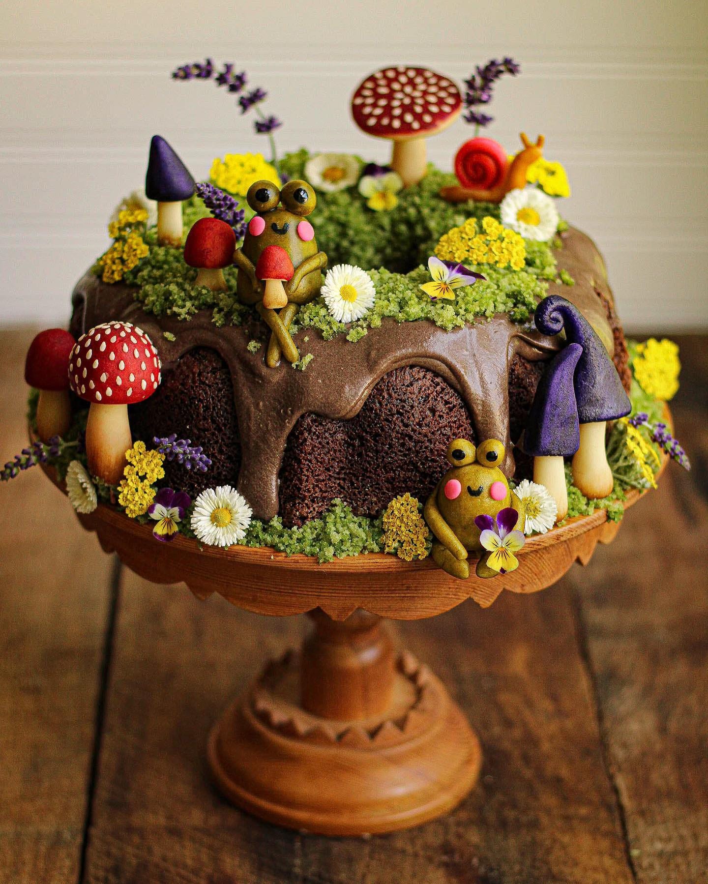 chocolate bundt cake decorated with pastry mushrooms and frogs